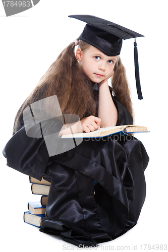 Image of girl in black academic cap and gown reading big blue book