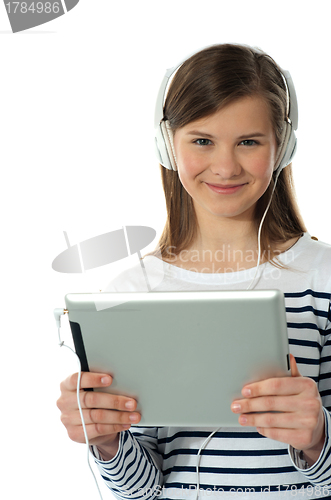 Image of Beautiful girl listening to music via wireless tablet