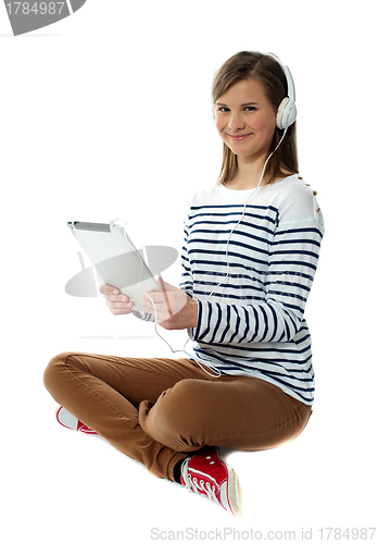 Image of Seated girl enjoying music on portable device