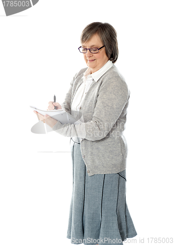 Image of Senior woman writing in spiral notebook