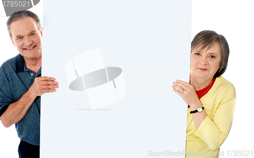 Image of Senior couple standing behind blank billboard