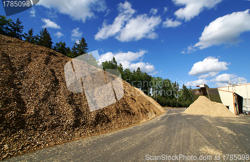 Image of bio power plant with storage of wooden fuel against blue sky