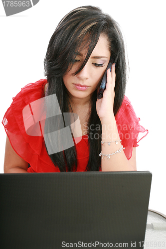 Image of Serious business woman looking at laptop screen while talking on