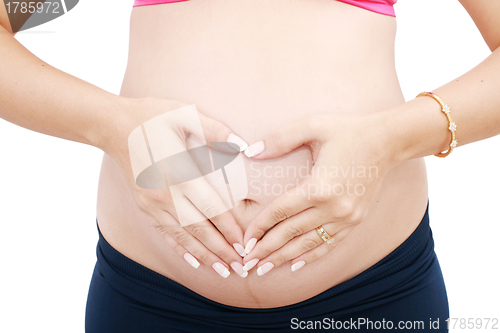 Image of Woman holding her hands in a heart shape on her pregnant belly 