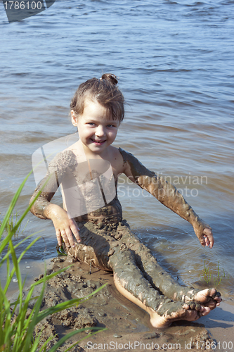 Image of Baby girl in the mud on the river