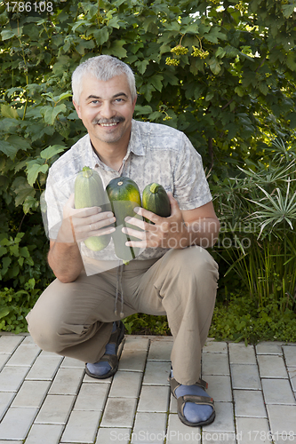 Image of Satisfied man with three zucchin