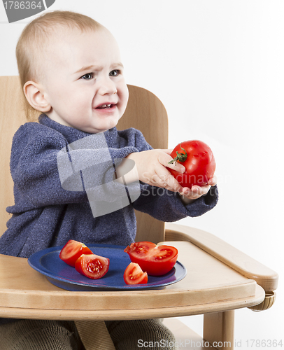 Image of young child eating tomatoes in high chair