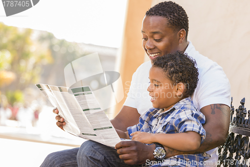 Image of Mixed Race Father and Son Reading Park Brochure Outside