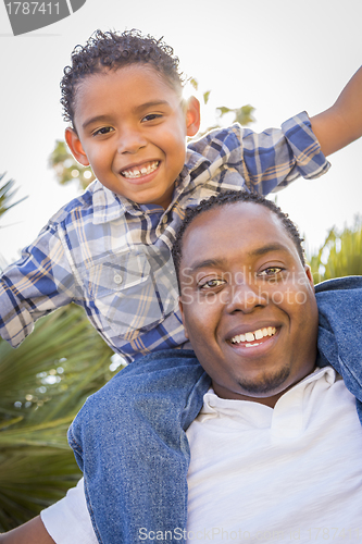 Image of Mixed Race Father and Son Playing Piggyback in Park