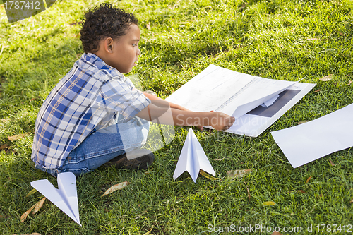 Image of Mixed Race Boy Learning How to Fold Paper Airplanes