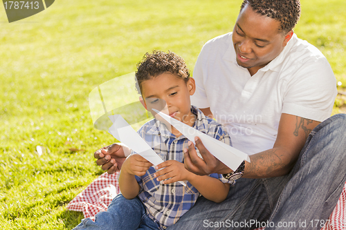 Image of Mixed Race Father and Son Playing with Paper Airplanes