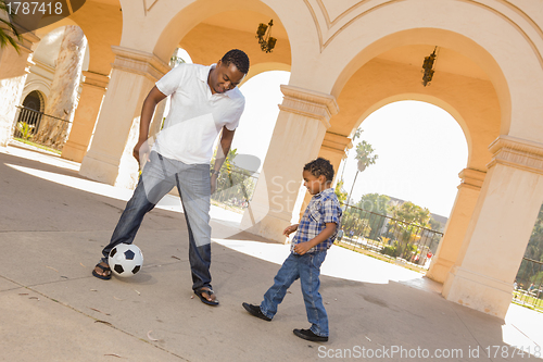 Image of Mixed Race Father and Son Playing Soccer in the Courtyard