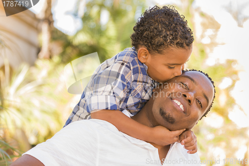 Image of Mixed Race Father and Son Playing Piggyback in Park