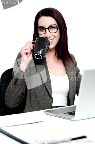 Image of Corporate woman enjoying coffee at work desk