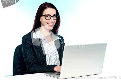 Image of Cheerful corporate woman using laptop