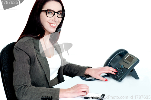 Image of Attractive female executive dialing clients number