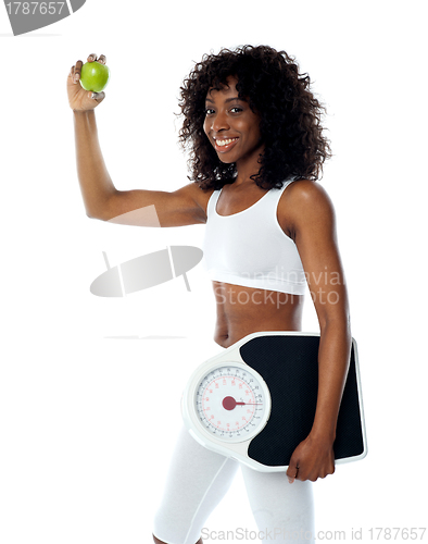 Image of Athlete holding green apple and weighing machine