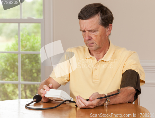 Image of Senior man taking blood pressure at home