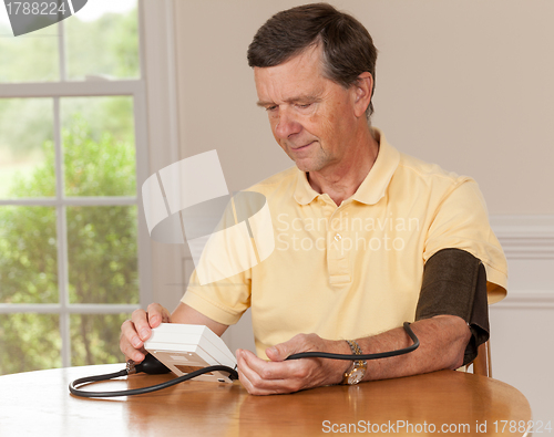 Image of Senior man taking blood pressure at home