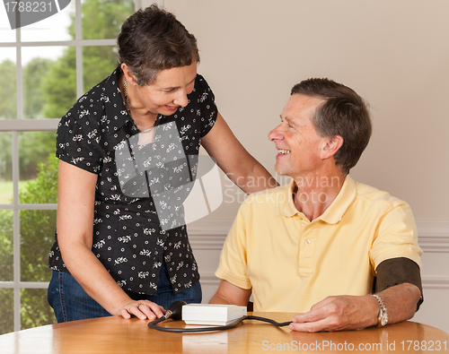 Image of Senior man taking blood pressure with wife
