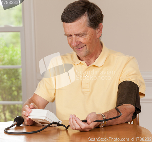 Image of Senior man taking blood pressure at home