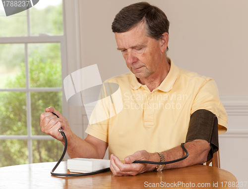 Image of Senior man taking blood pressure at home