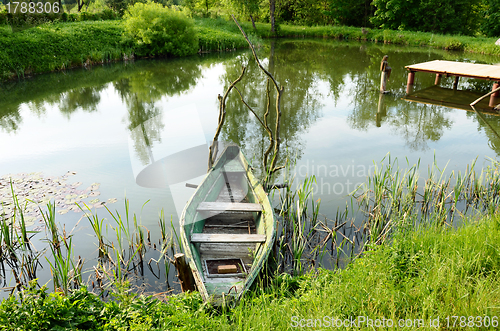 Image of Old wooden boat stand moored on pond shore bridge 