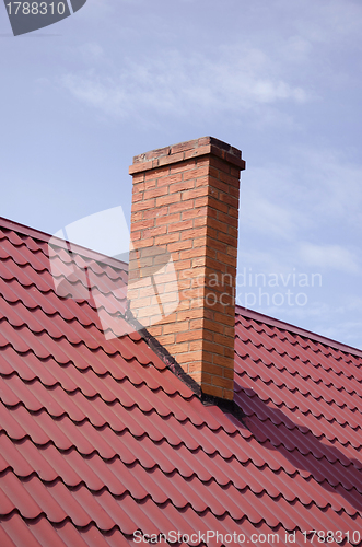 Image of Brown tiled roof yellow brick chimney on sky 