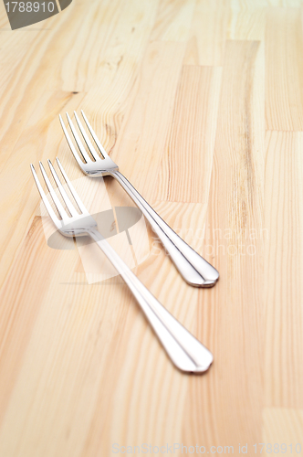 Image of two fork on a pinewood table