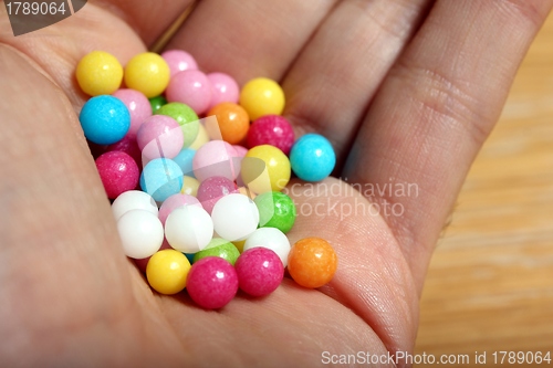 Image of colored sugar balls in a humand hand