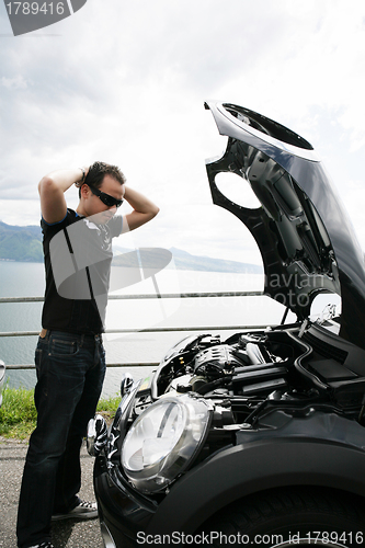 Image of sad man looking at his broken car 