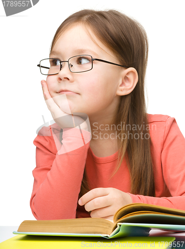 Image of Cute little girl is dreaming while reading book