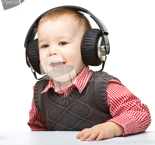 Image of Cute little boy enjoying music using headphones