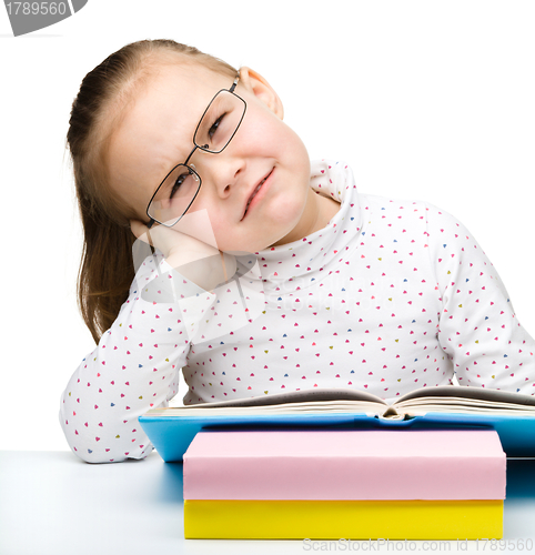 Image of Cute little girl is tired of reading her book
