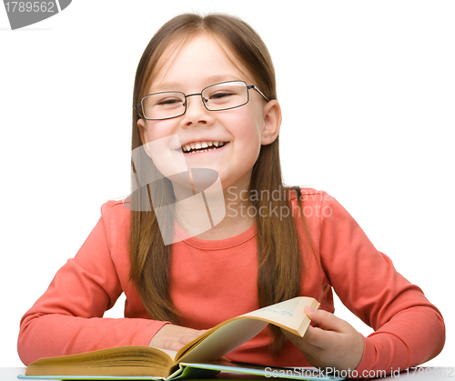 Image of Cute cheerful little girl reading book