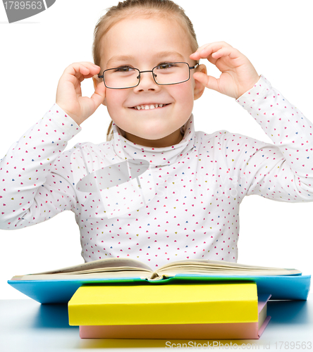 Image of Cute cheerful little girl reading book