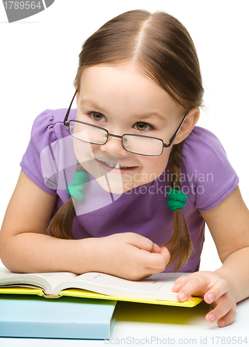 Image of Cute cheerful little girl reading book