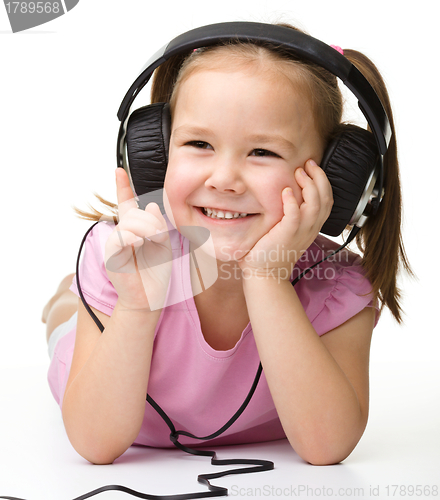 Image of Cute little girl enjoying music using headphones