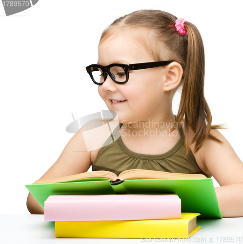 Image of Cute cheerful little girl reading book