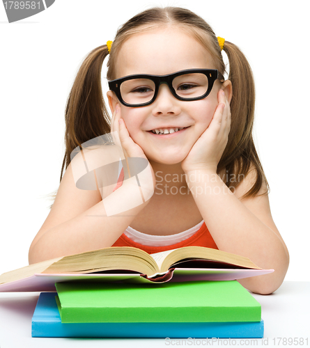 Image of Cute cheerful little girl reading book