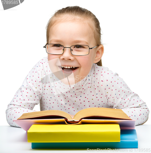 Image of Cute cheerful little girl reading book