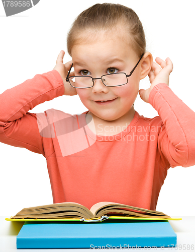 Image of Cute cheerful little girl reading book