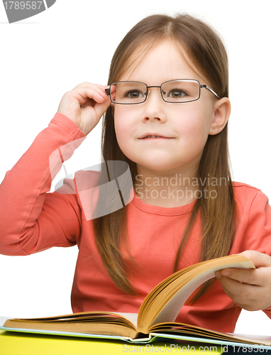 Image of Cute little girl reading book wearing glasses