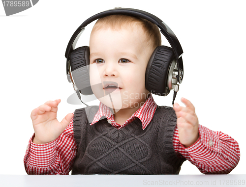 Image of Cute little boy enjoying music using headphones