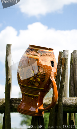 Image of Clay broken pitcher hang on wooden woven fence 