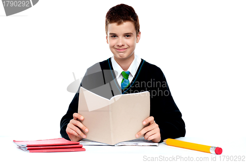 Image of Cute school kid holding notebook and reading