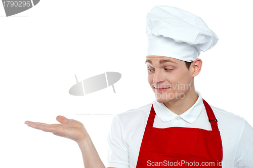 Image of Chef looking at his hand. Offering cooked food
