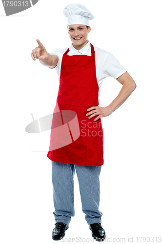 Image of Male chef in uniform pointing away and smiling