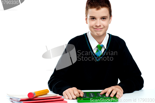 Image of Smiling young boy using calculator