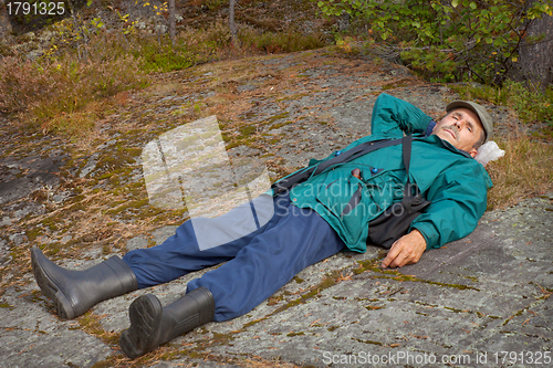 Image of Elderly tourist resting on the rock